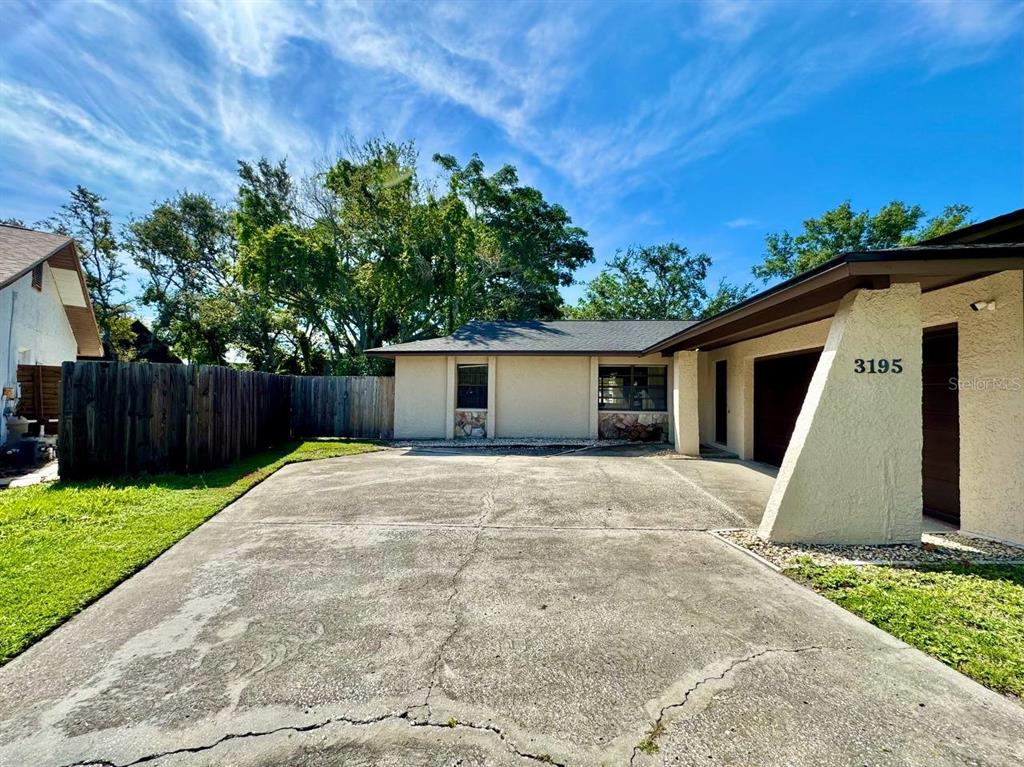 A concrete driveway leads to the front of a single-story house with a garage — 3195 CHAMBLEE LANE, CLEARWATER, FL
