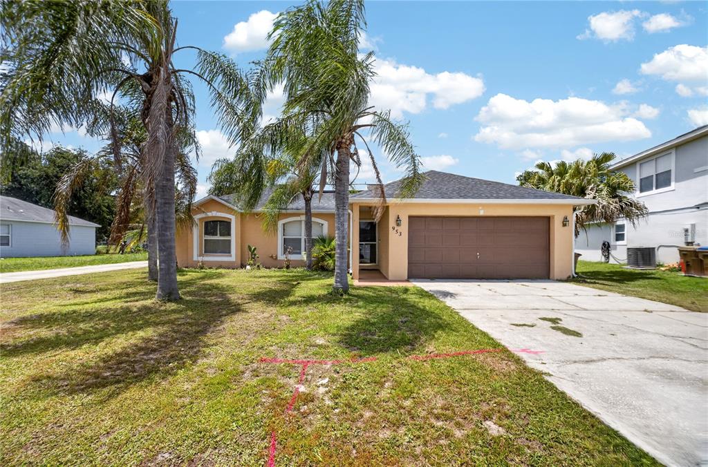 A single-story house with a tan exterior, a two-car garage, and palm trees in front — 953 GASCONY COURT, KISSIMMEE, FL