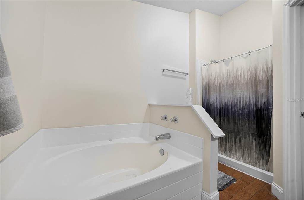 A bathroom features a white soaking tub, a tiled surround, and a shower with curtains — 953 GASCONY COURT, KISSIMMEE, FL