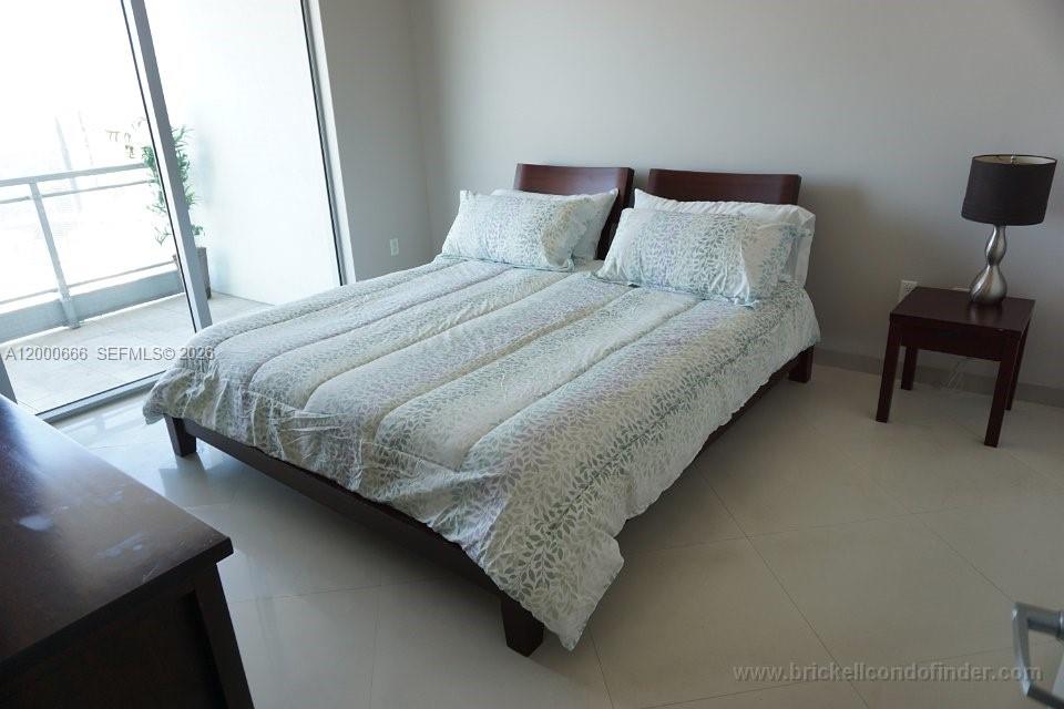 A bedroom features a bed with a patterned comforter, a nightstand, and a balcony door — 90 SW 3rd St # 3505, Miami FL 33130, MIAMI, FL