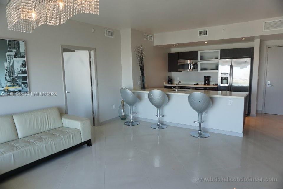 A modern living room features a white sofa, a kitchen island, and three silver barstools — 90 SW 3rd St # 3505, Miami FL 33130, MIAMI, FL