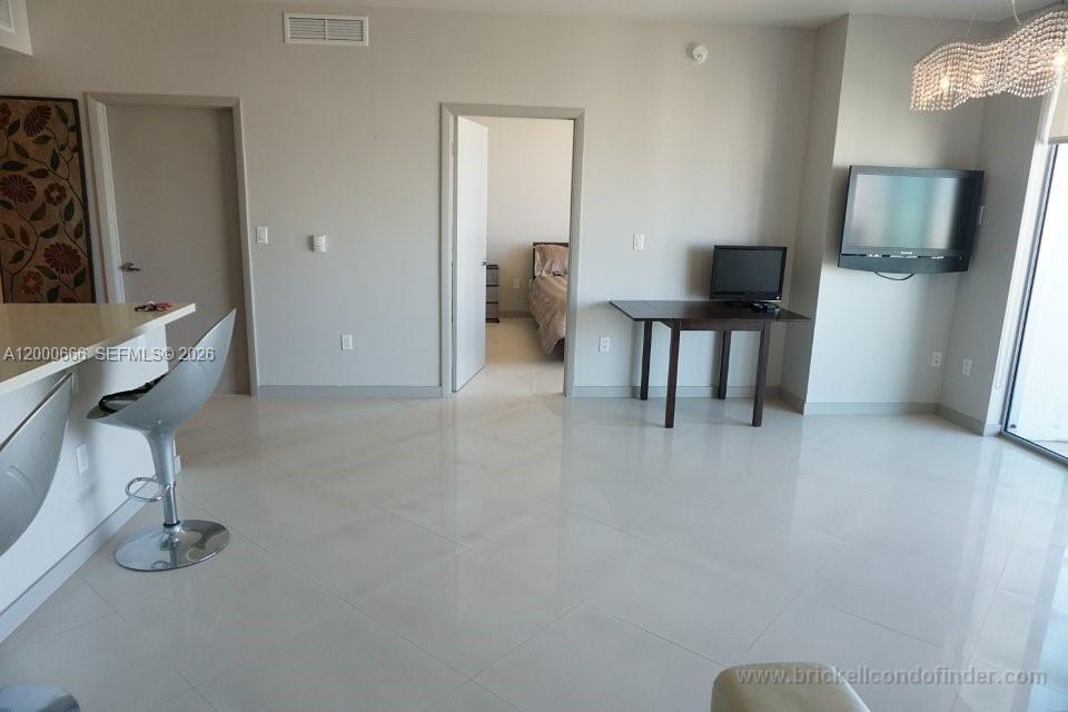 A modern living area features white tile floors, a breakfast bar, and a bedroom doorway — 90 SW 3rd St # 3505, Miami FL 33130, MIAMI, FL