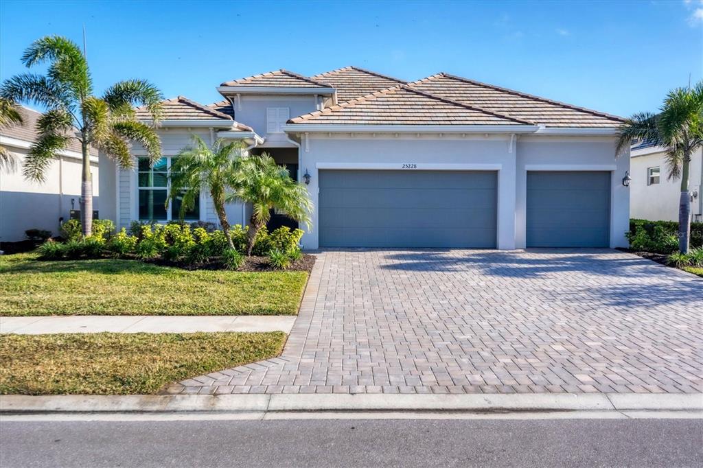 A single-story house with a paved driveway, a three-car garage, and palm trees in front — 25228 LONGMEADOW DRIVE, PUNTA GORDA, FL