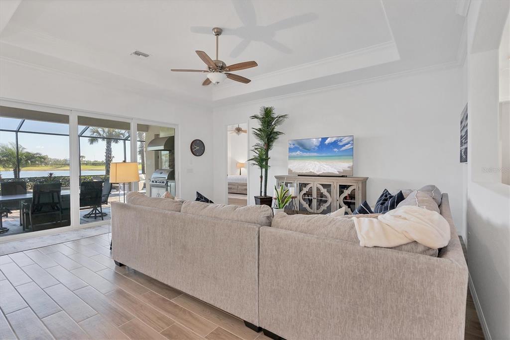 A living room features a large sectional sofa, a television on a console, and sliding glass doors — 25228 LONGMEADOW DRIVE, PUNTA GORDA, FL