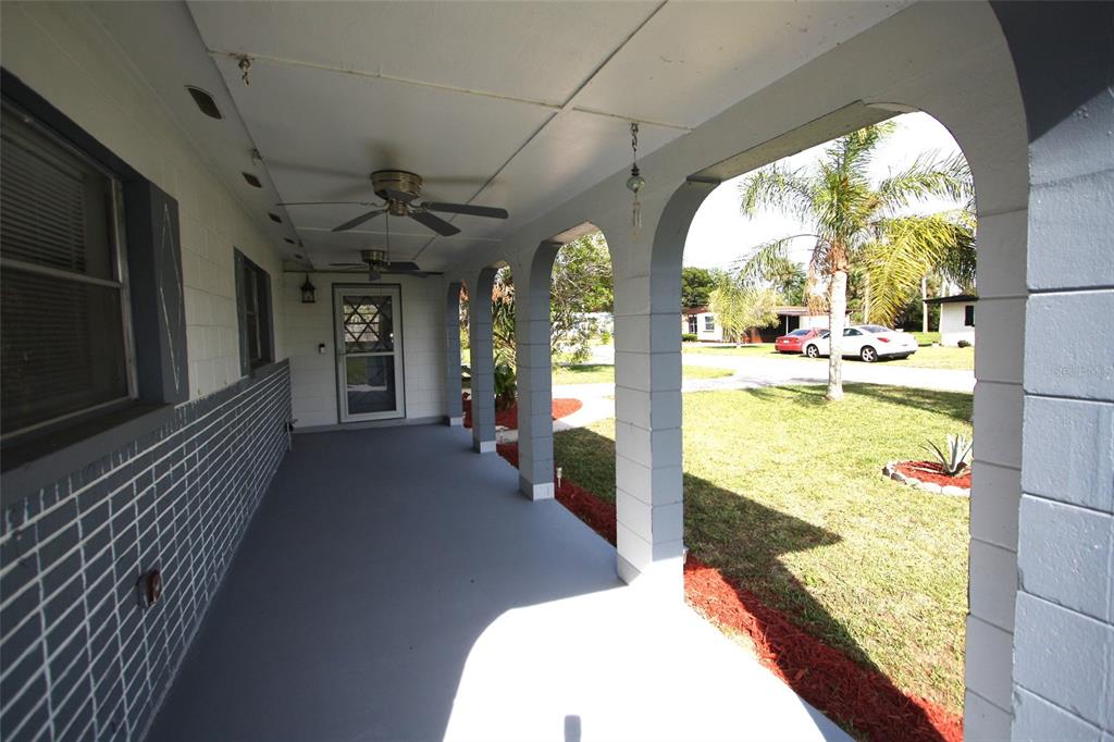 A covered porch with gray painted flooring, brick walls, and arched concrete support columns — 141 W CONNECTICUT AVENUE, EDGEWATER, FL