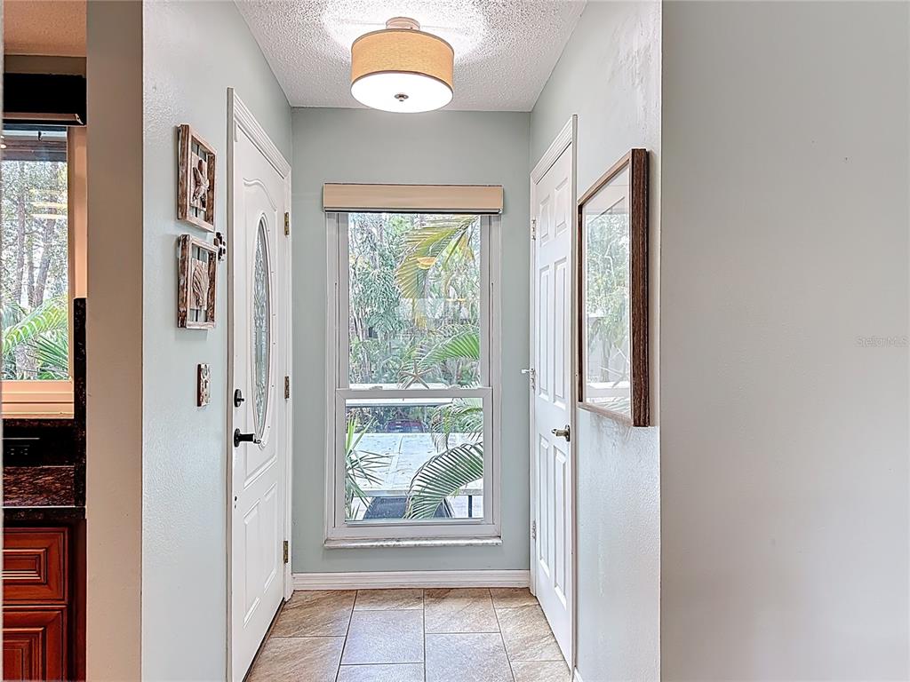 A bright entryway features a central window, tiled flooring, and two white doors — 1715 PELICAN COVE ROAD UNIT GL438, SARASOTA, FL