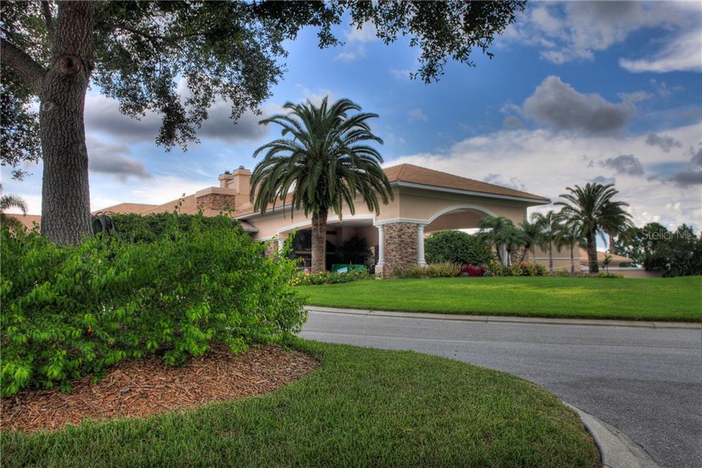 A large building with a covered entrance and palm trees sits behind a manicured lawn — 5270 HYLAND HILLS AVENUE UNIT 1722, SARASOTA, FL