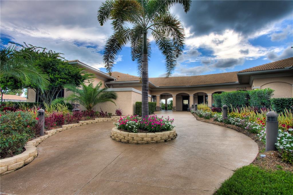 A circular driveway with a central palm tree and flower bed leads to a building entrance — 5270 HYLAND HILLS AVENUE UNIT 1722, SARASOTA, FL
