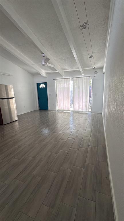 A spacious room with wood-look tile flooring, a vaulted ceiling with beams, and sliding doors — 500 N JEFFERSON AVENUE UNIT G3, SARASOTA, FL