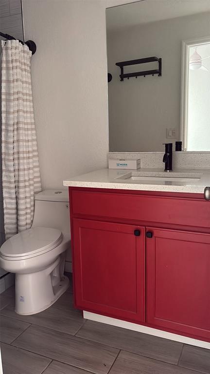 A bathroom features a white toilet, a red vanity cabinet, and a light-colored countertop — 500 N JEFFERSON AVENUE UNIT G3, SARASOTA, FL