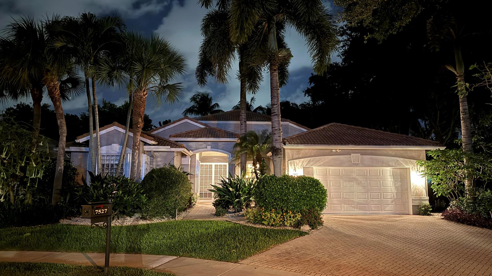 A single-story house with a tiled roof, palm trees, and a paved driveway at night — 7527 Monticello Way, Boynton Beach FL 33437, BOYNTON BEACH, FL