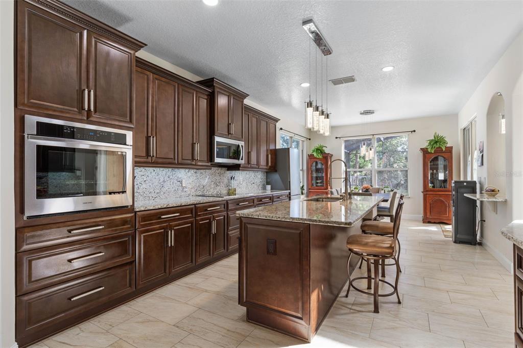 A kitchen with dark wood cabinets, granite countertops, a center island, and stainless steel appliances — 38 BREWSTER LANE, PALM COAST, FL