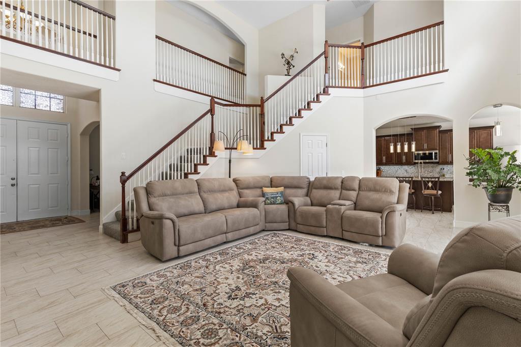 A spacious living room features a large sectional sofa, a patterned rug, and a staircase — 38 BREWSTER LANE, PALM COAST, FL