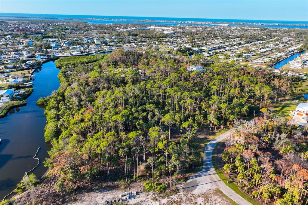 An aerial view shows a wooded lot bordered by a canal and a paved road — 971 LAMPP DRIVE, ENGLEWOOD, FL