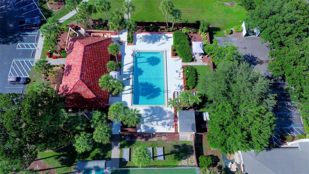 An aerial view shows a rectangular swimming pool next to a building with a red roof — 3006 CARING WAY UNIT 210, PORT CHARLOTTE, FL