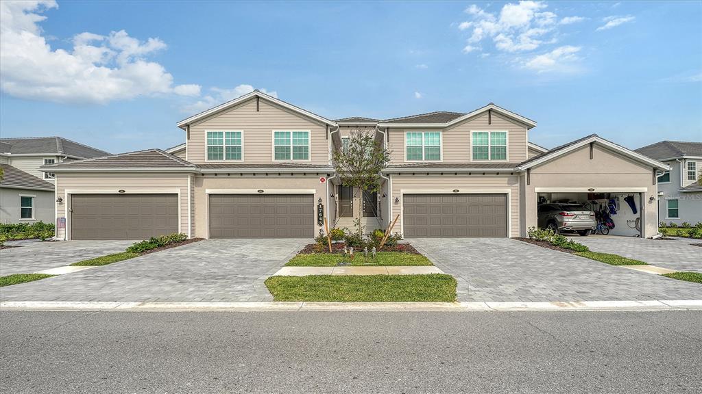 A two-story duplex with beige siding, two garage doors, and a paved driveway — 17645 BOROCAY COURT UNIT 201, VENICE, FL
