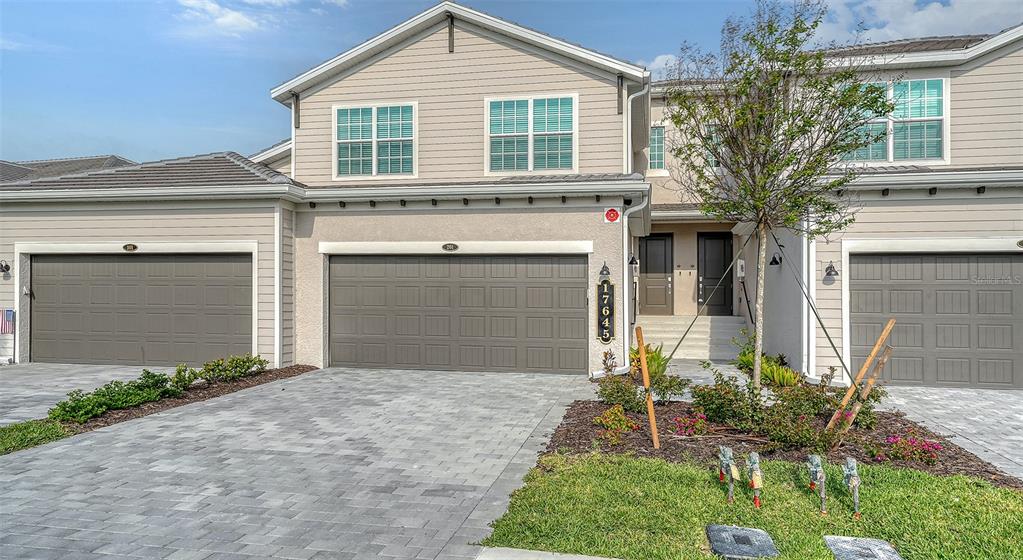 A multi-unit residential building features gray garage doors, beige siding, and a paved driveway — 17645 BOROCAY COURT UNIT 201, VENICE, FL