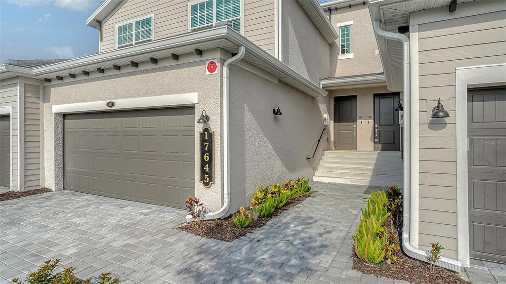 The exterior of a two-story townhouse features a garage, a paved walkway, and front doors — 17645 BOROCAY COURT UNIT 201, VENICE, FL
