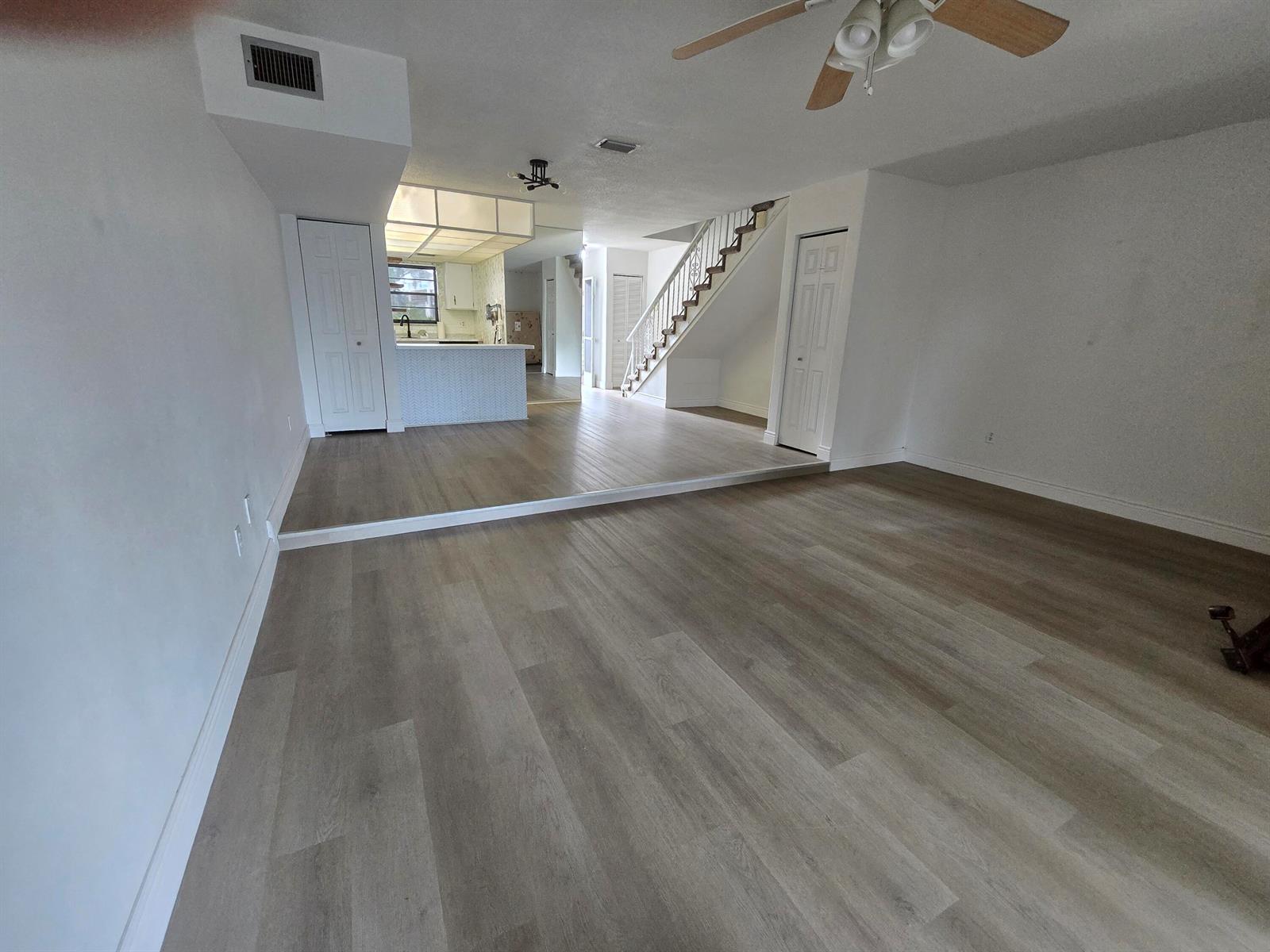 A living room with light wood-look flooring features a sunken floor and a staircase — 2153 N 14th Avenue # 2153, Hollywood FL 33020, HOLLYWOOD, FL