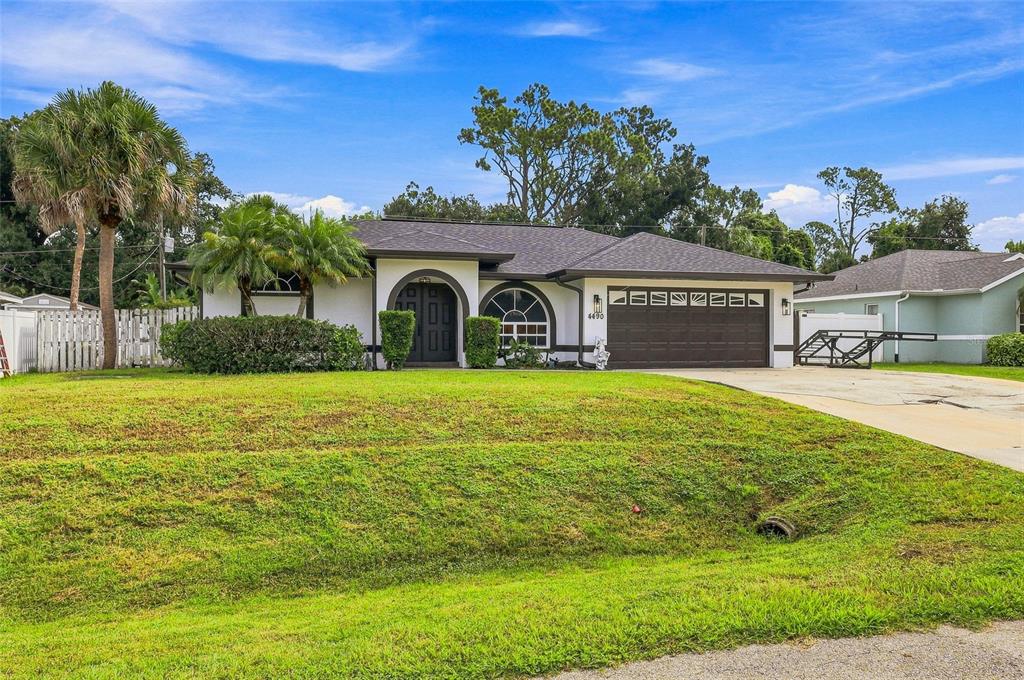 A single-story house with a brown garage door, arched entryway, and a grassy front yard — 4490 COMPTON LANE, NORTH PORT, FL