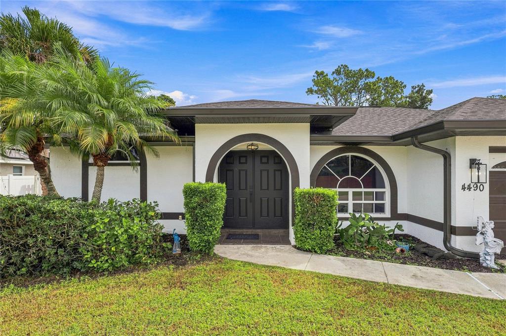 A white house exterior features a dark arched double door and a large arched window — 4490 COMPTON LANE, NORTH PORT, FL