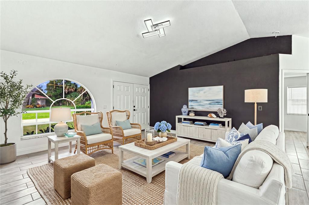 A living room features a vaulted ceiling, a dark accent wall, and coastal-style furniture — 4490 COMPTON LANE, NORTH PORT, FL