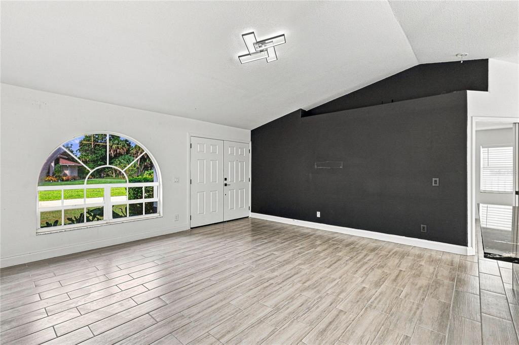 A living room features a vaulted ceiling, a black accent wall, and a large arched window — 4490 COMPTON LANE, NORTH PORT, FL