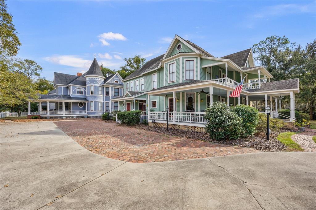 A large, two-story Victorian-style house with green and blue siding and a brick driveway — 205 SE 7TH STREET, GAINESVILLE, FL