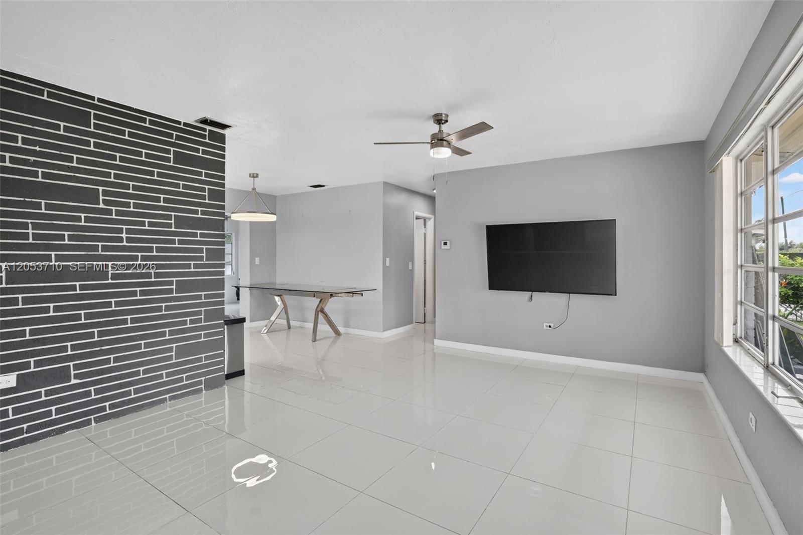 A living room features light gray walls, white tile floors, and a dark brick accent wall — 2331 Flamingo Dr, Miramar FL 33023, MIRAMAR, FL