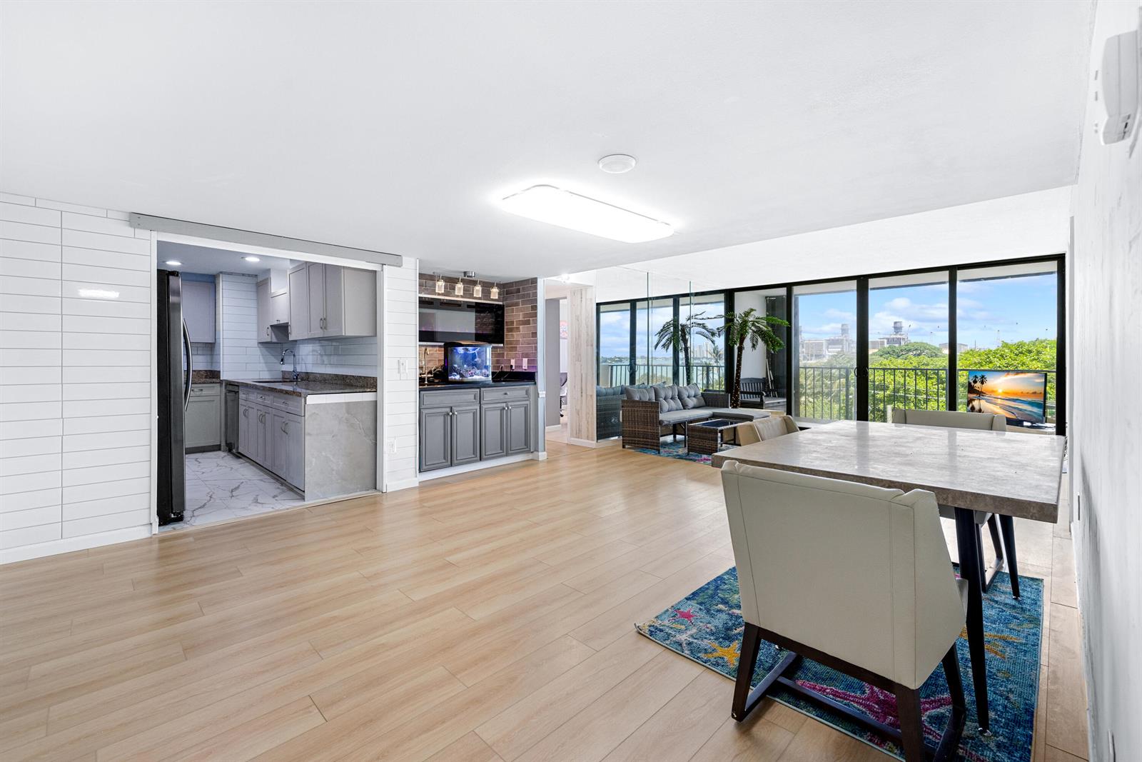 An open-concept living and dining area features light wood flooring, a kitchen, and balcony views — 5600 N Flagler Drive # 407, West Palm Beach FL 33407, WEST PALM BEACH, FL
