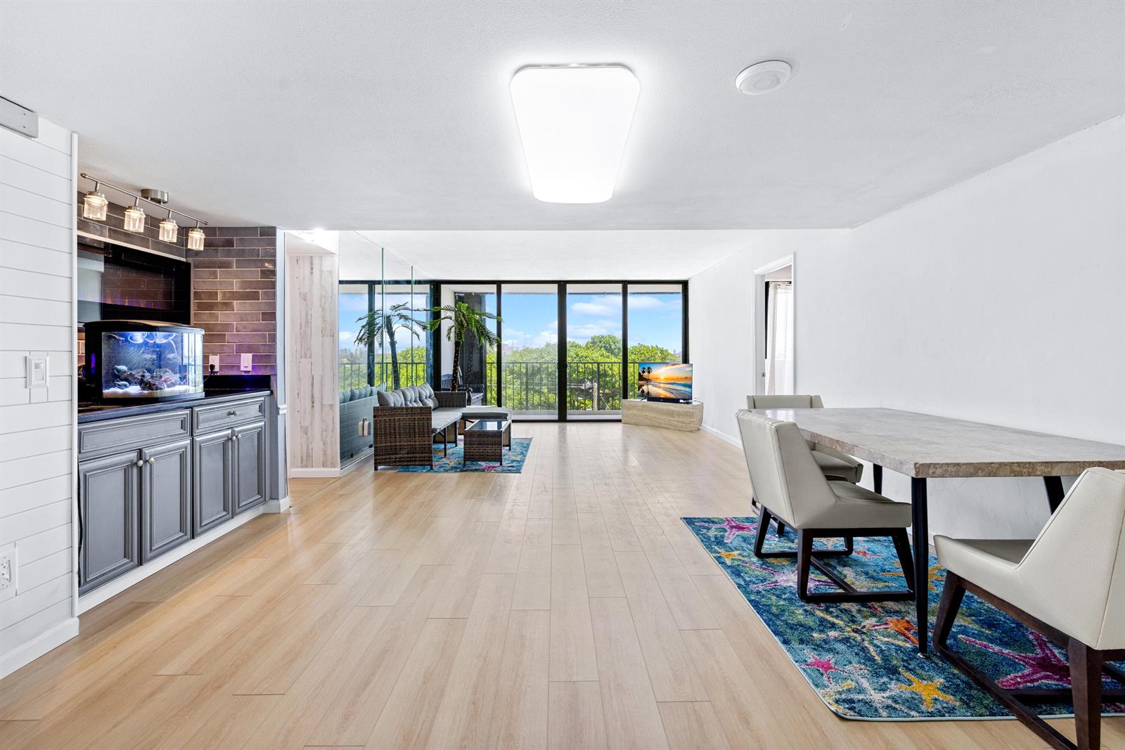 A bright, open-concept living and dining area features light wood flooring and a wet bar — 5600 N Flagler Drive # 407, West Palm Beach FL 33407, WEST PALM BEACH, FL