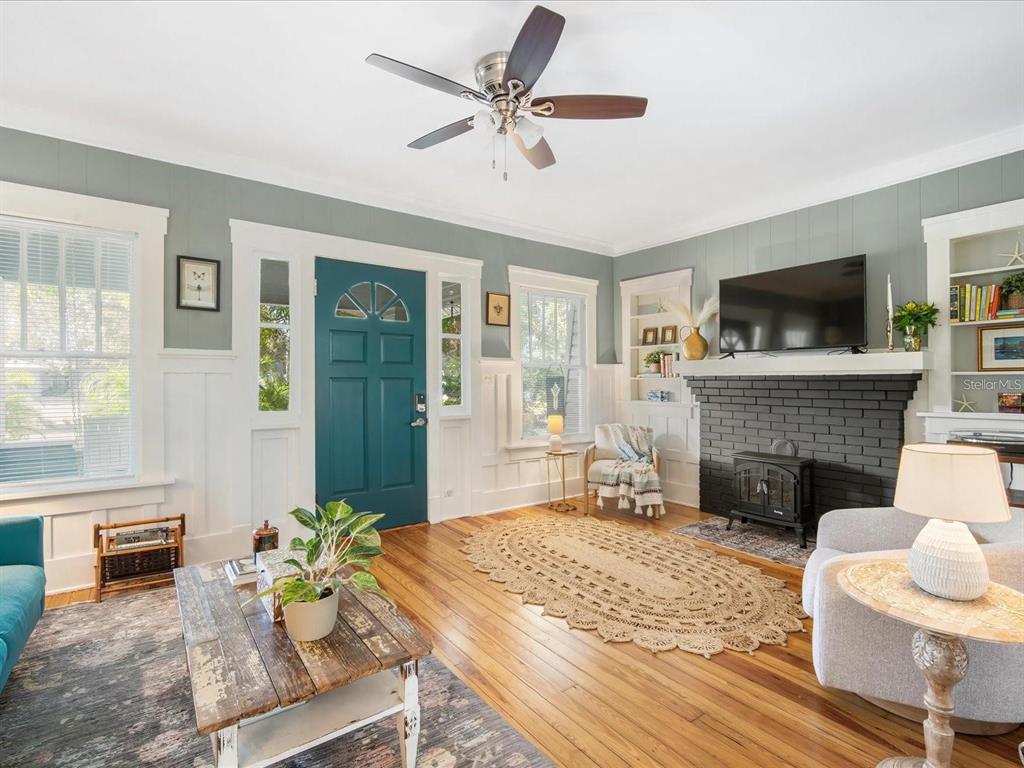 A living room features a teal front door, a black brick fireplace, and hardwood floors — 2822 4TH AVENUE W, BRADENTON, FL