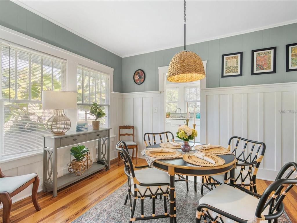 A dining room with a round table, rattan chairs, board and batten walls, and wood floors — 2822 4TH AVENUE W, BRADENTON, FL