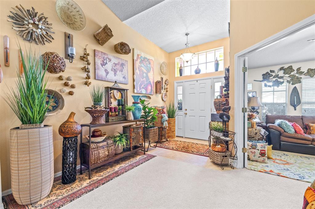 A bright entryway features a console table, wall decor, and a doorway leading to a living room — 7113 CROMWELL PARK LANE, APOLLO BEACH, FL