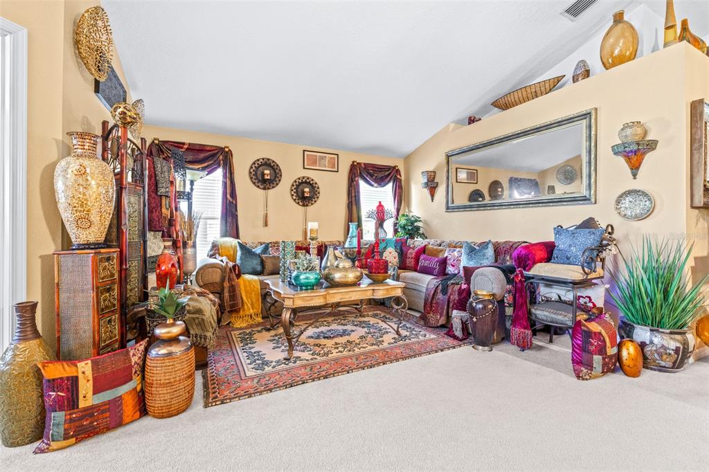 A living room features a large sectional sofa, a coffee table, and eclectic global-inspired decor — 7113 CROMWELL PARK LANE, APOLLO BEACH, FL