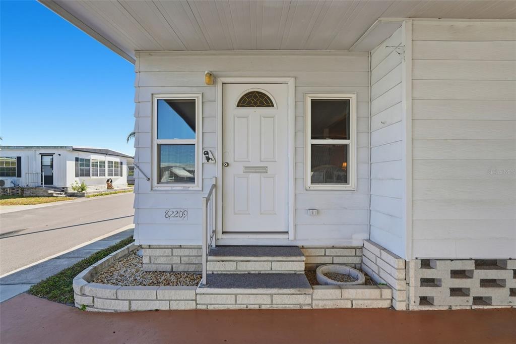 A white mobile home exterior features a front door with a small arched window — 82209 F STREET N UNIT 209, PINELLAS PARK, FL