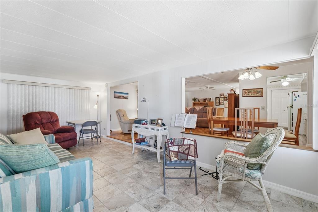 A living room with tile flooring, a pass-through window to the dining area, and furniture — 82209 F STREET N UNIT 209, PINELLAS PARK, FL