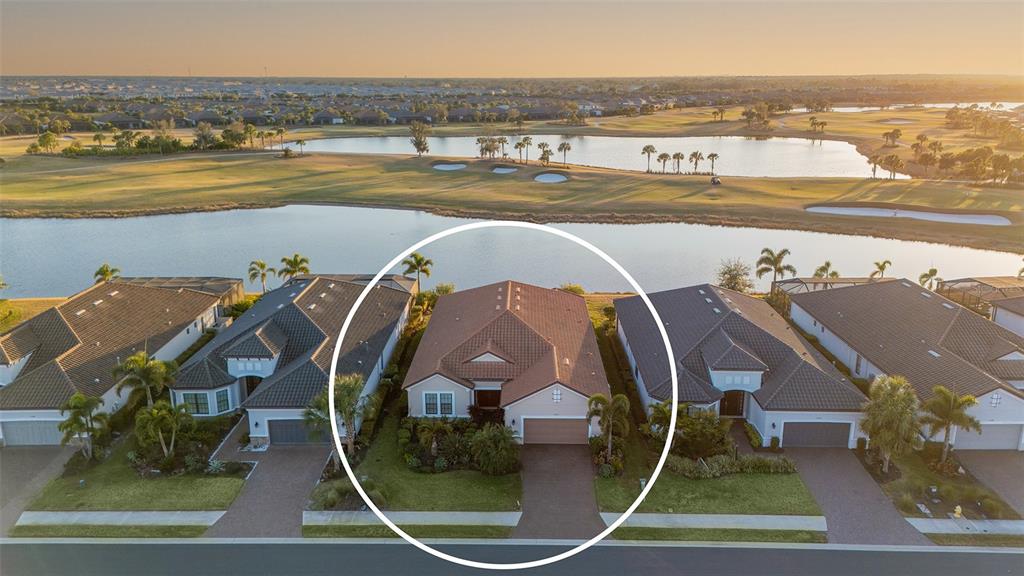 An aerial view shows a single-story house with a tiled roof situated near a lake — 15410 DERNA TERRACE, LAKEWOOD RANCH, FL