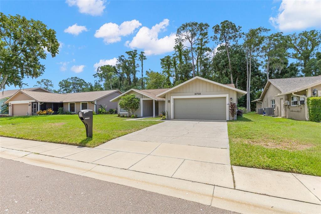 A single-story house with a beige exterior, a two-car garage, and a concrete driveway — 2718 WOODHALL TERRACE, PALM HARBOR, FL