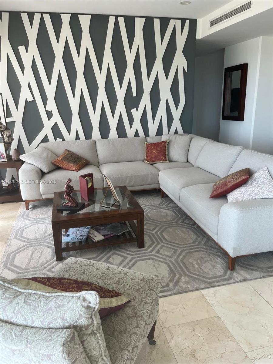 A living room features a large sectional sofa, a coffee table, and a geometric wall design — Av Bonampak sm 3-01 # 305, Ca, Ca