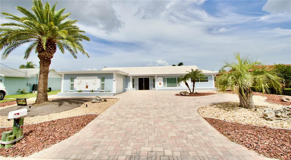 A single-story house with a paved driveway, two palm trees, and a light blue exterior — 5339 BOWLINE BEND, NEW PORT RICHEY, FL