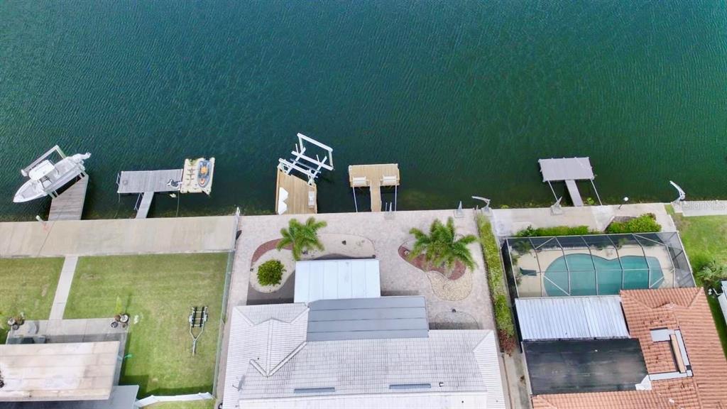 An aerial view shows a waterfront house with a pool, dock, and boat lift — 5339 BOWLINE BEND, NEW PORT RICHEY, FL