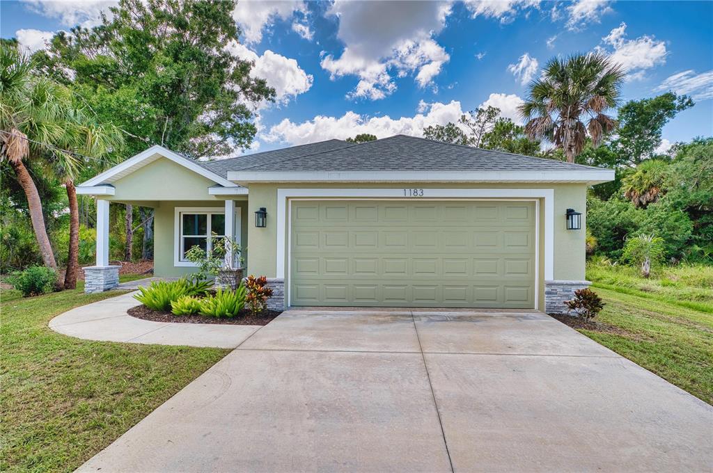 A single-story house with a green exterior, a two-car garage, and a covered front porch — 1183 CEDAR AVENUE, ENGLEWOOD, FL