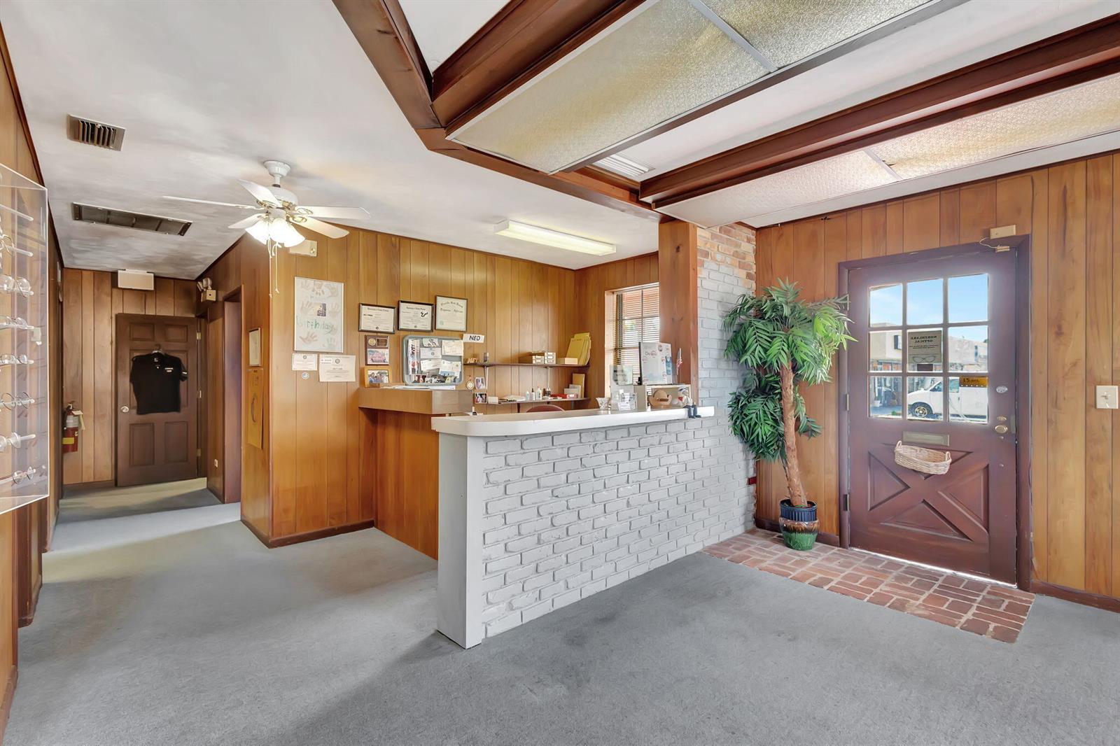 A reception area features wood-paneled walls, a white brick counter, and a glass-paned entry door — 610 Northlake Boulevard, Lake Park FL 33408, LAKE PARK, FL