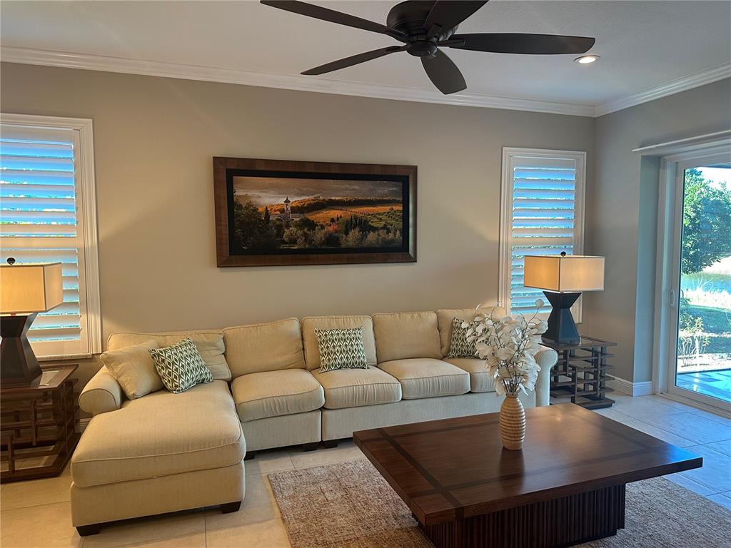 A living room features a beige sectional sofa, a wooden coffee table, and landscape wall art — 7135 KENSINGTON COURT, UNIVERSITY PARK, FL