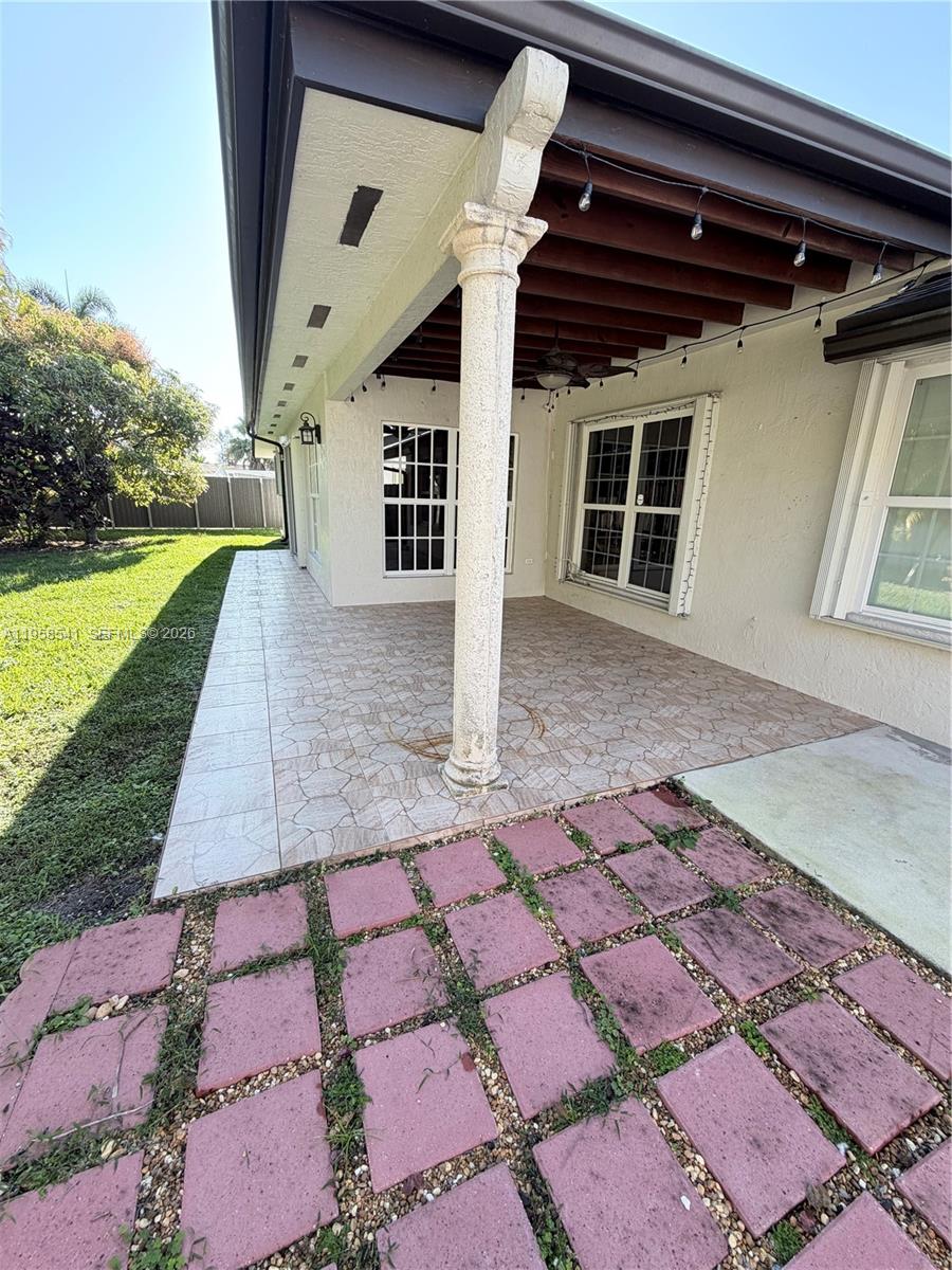 A covered patio features a decorative column, tiled flooring, and an adjacent brick paver area — 12821 SW 147th Lane Rd, Miami FL 33186, MIAMI, FL