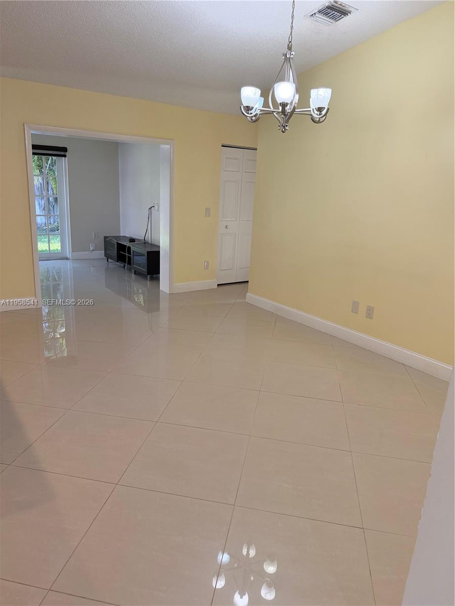 A dining room with yellow walls, a chandelier, and light-colored tile flooring — 12821 SW 147th Lane Rd, Miami FL 33186, MIAMI, FL