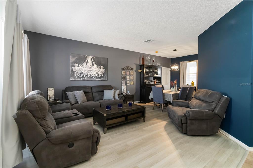A living room and dining area feature gray walls, dark furniture, and light wood-look flooring — 633 LINNET COURT, KISSIMMEE, FL