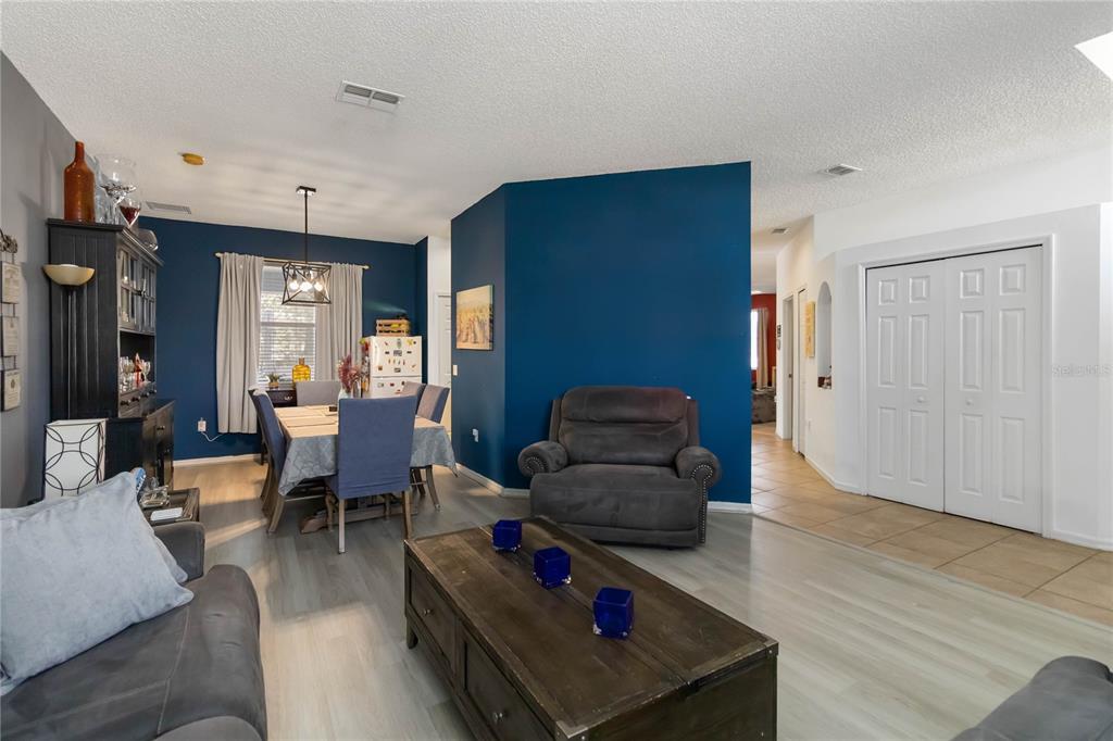 A living room and dining area feature blue accent walls, gray flooring, and white doors — 633 LINNET COURT, KISSIMMEE, FL