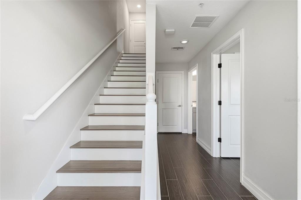 A staircase with wood-look treads and white risers leads to a landing with white doors — 4941 W PRICE AVENUE UNIT 3, TAMPA, FL